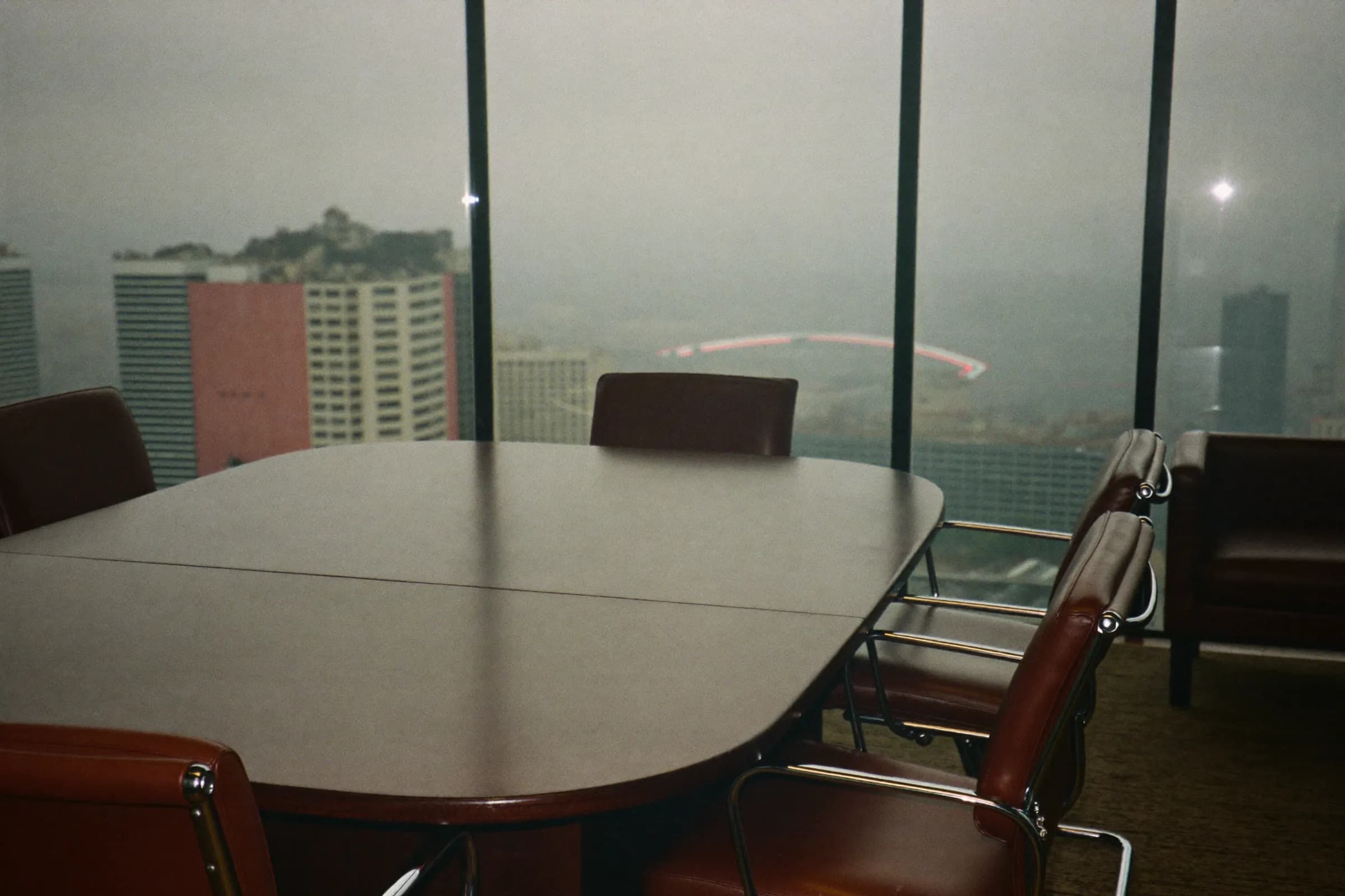 An empty boardroom overlooking a skyline in fog