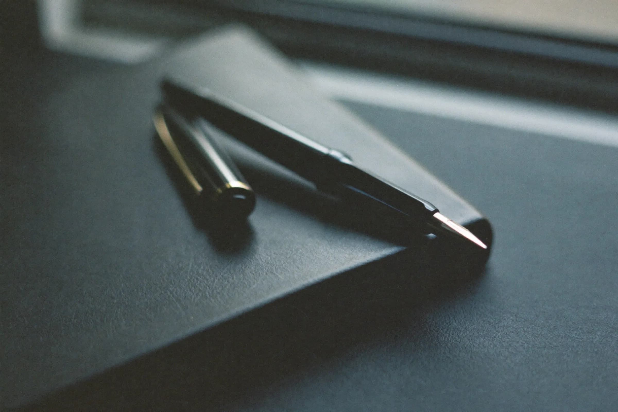 A fountain pen resting on a leather-bound ledger