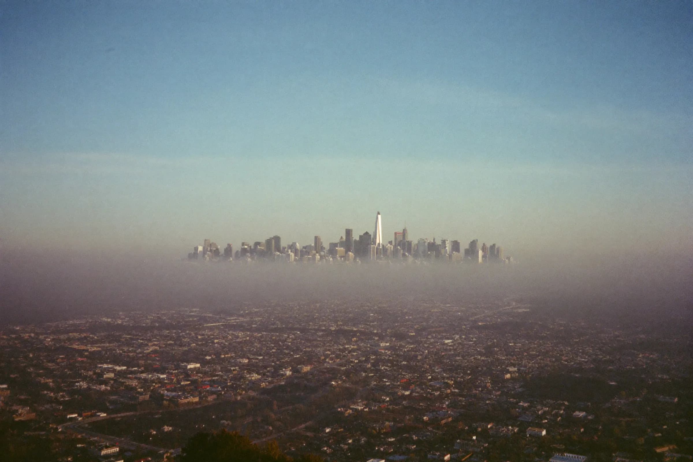 A city skyline at blue hour above a layer of fog