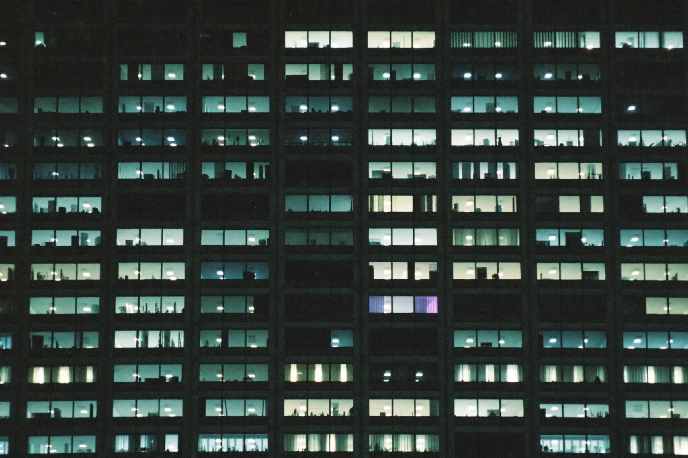 A grid of lit office windows on a tower at night